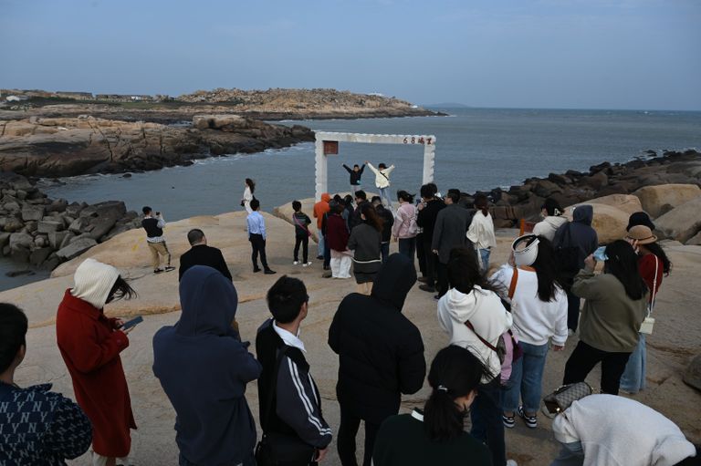 رجل يلتقط صورة لامرأة تحت إطار أمام مضيق تايوان