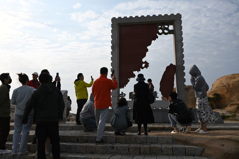 رجل يلتقط صورة لامرأة تحت إطار أمام مضيق تايوان