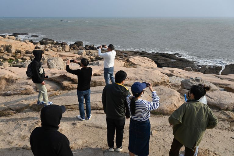 رجل يلتقط صورة لامرأة تحت إطار أمام مضيق تايوان