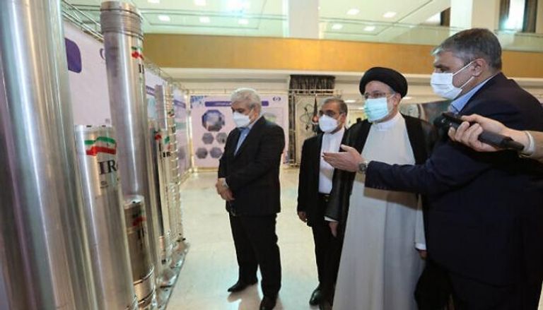الرئيس الإيراني إبراهيم رئيسي، يستمع إلى شرح أثناء مشاهدة جهاز طرد مركزي متقدم 