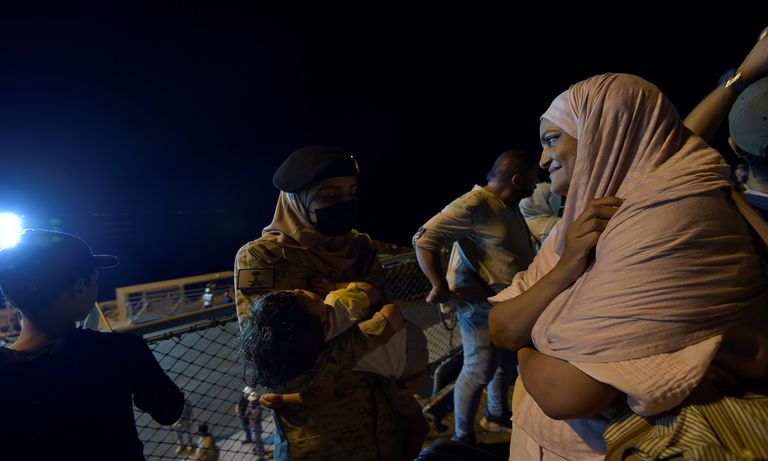 عسكرية سعودية تحمل طفلا تم إجلاؤه من السودان