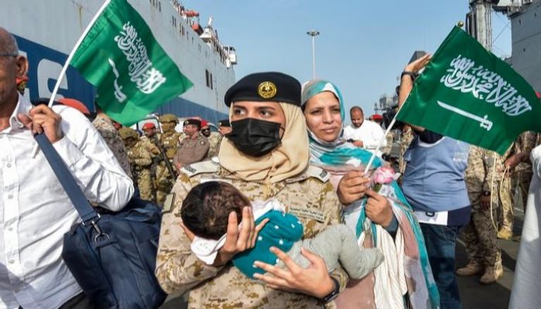 مجندة بالقوات البحرية الملكية السعودية تحمل طفلا قادما من السودان
