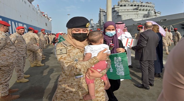 مجندة بالقوات البحرية الملكية السعودية تحمل طفلا قادما من السودان