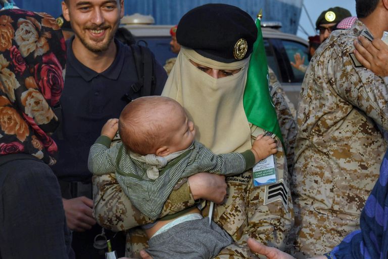 مجندة بالقوات البحرية الملكية السعودية تحمل طفلا قادما من السودان