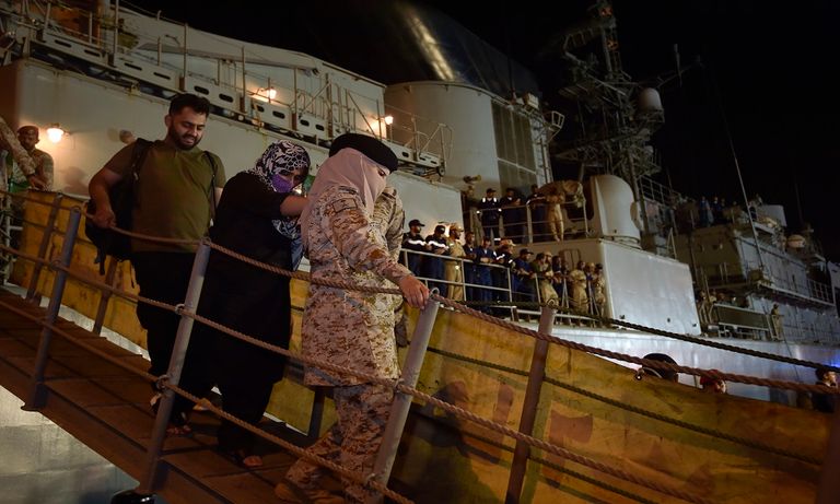 مجندة بالقوات البحرية الملكية السعودية تحمل طفلا قادما من السودان