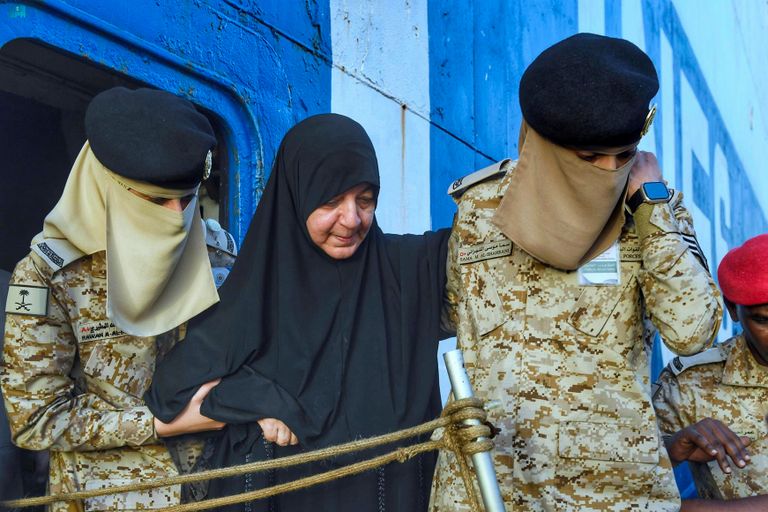 مجندة بالقوات البحرية الملكية السعودية تحمل طفلا قادما من السودان