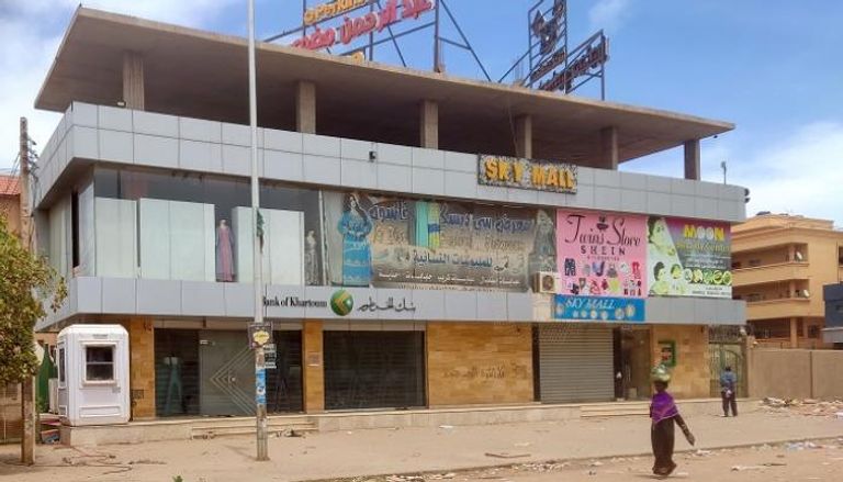 سيدة سودانية تمر قرب محال تجارية مغلقة بالخرطوم