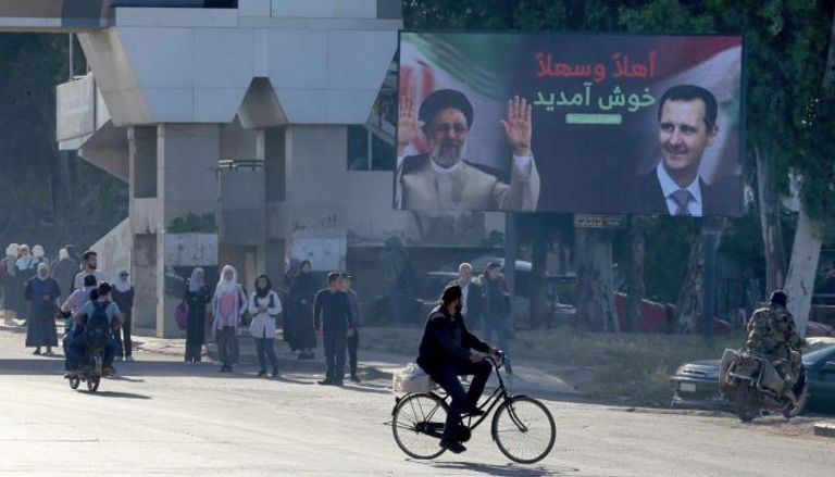 لوحة إعلانية بدمشق تحمل صور بشار الأسد وإبراهيم رئيسي