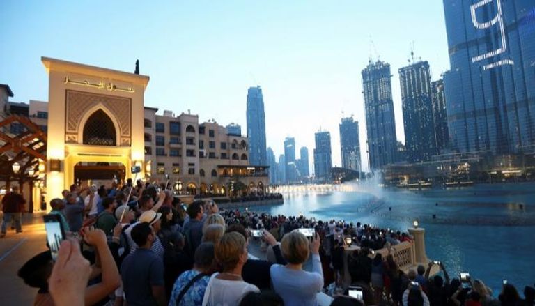 سائحون يتجمعون لمشاهدة نافورة موسيقية أمام برج خليفة  في دبي