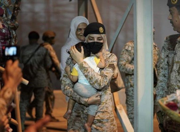 المجندة السعودية وهي تحتضن طفلة قادمة من السودان