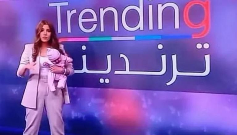 سيرينا غوكة تحمل رضيعتها أثناء تقديم برنامجها