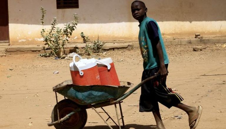 فتى سوداني يدفع عربة عليها صناديق مياه