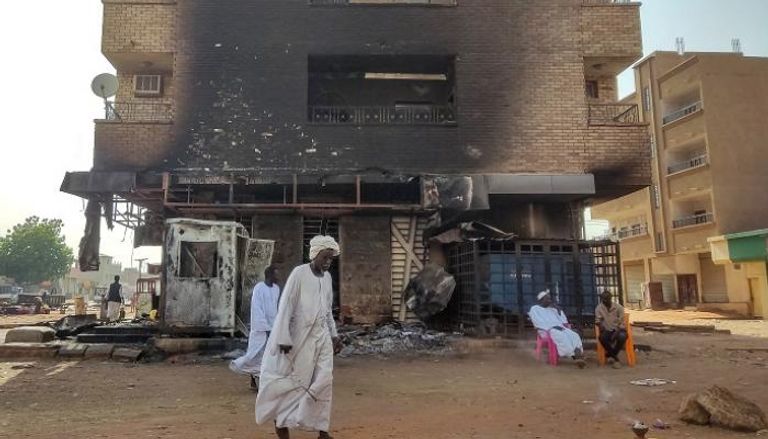 سودانيون قرب مبنى دمرته الاشتباكات بالخرطوم - الفرنسية