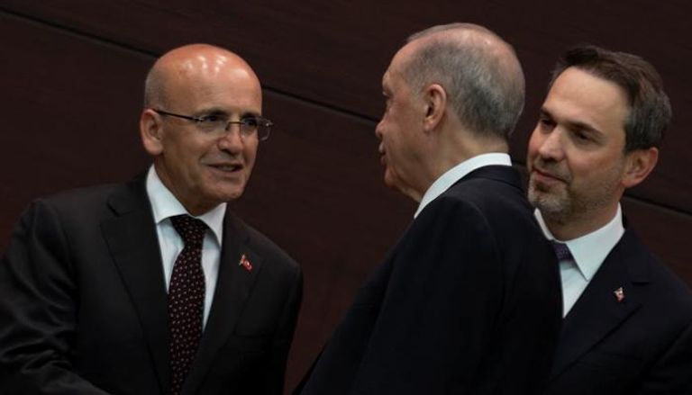 الرئيس التركي رجب طيب أردوغان يصافح وزير المالية محمد شيمشك
