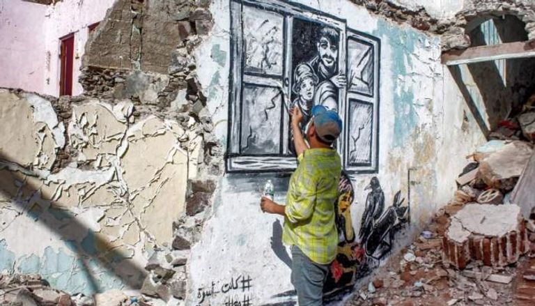 علاء روبيل يرسم إحدى جدارياته