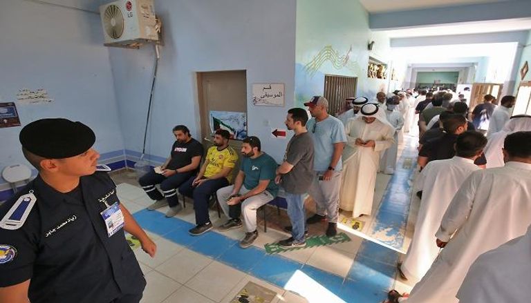 كويتيون يصطفون في مدرسة تحولت إلى مركز اقتراع للتصويت خلال الانتخابات البرلمانية في مدينة الكويت