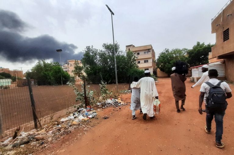 سودانيون يمرون قرب دخان متصاعد جراء الاشتباكات - أ.ف.ب مواطن سوداني وسط حطام منزل وسيارة محترقة جراء الاشتباكات - أ.ف.ب