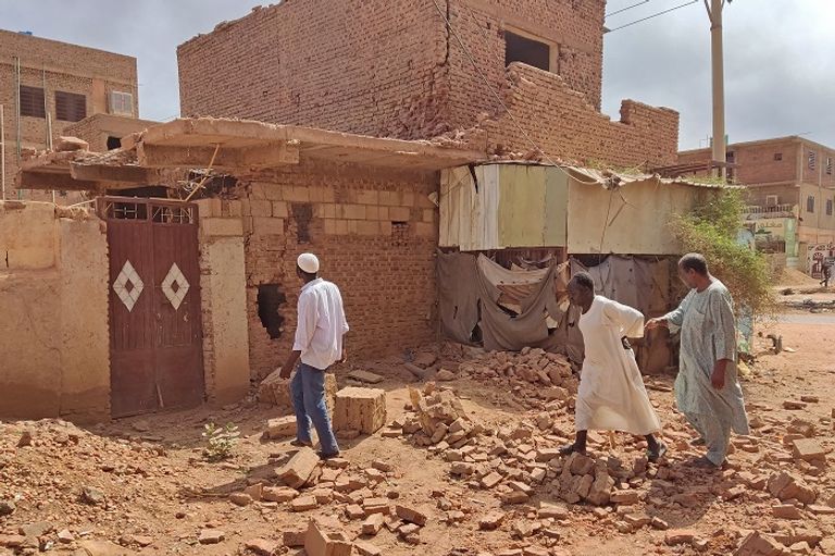 سودانيون يتفقدون الدمار بأحد المنازل جراء الاشتباكات - الفرنسية