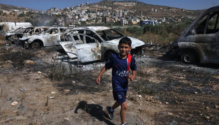 طفل قرب سيارات محترقة في الضفة الغربية