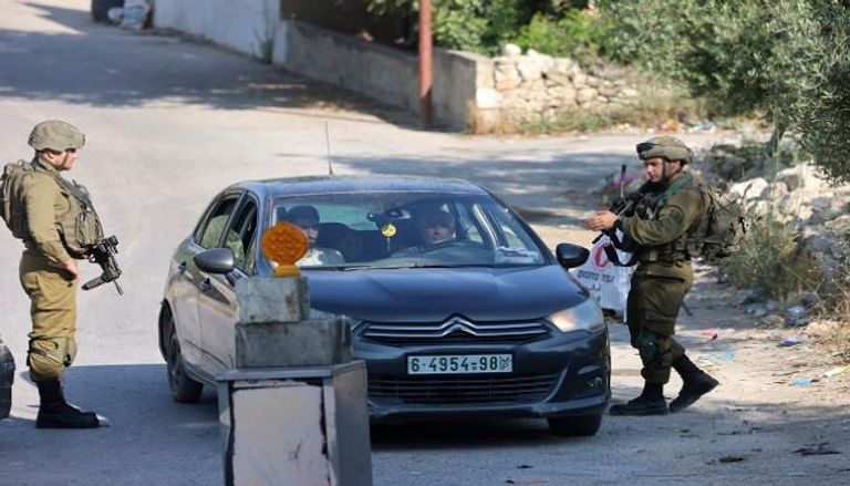 جنود إسرائيليون يقفون على حاجز على مدخل قرية عوريف الفلسطينية، جنوب مدينة نابلس