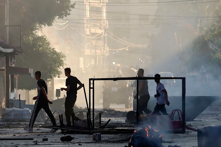 فلسطيني يحمل علما وسط النيران جراء المواجهات في جنين