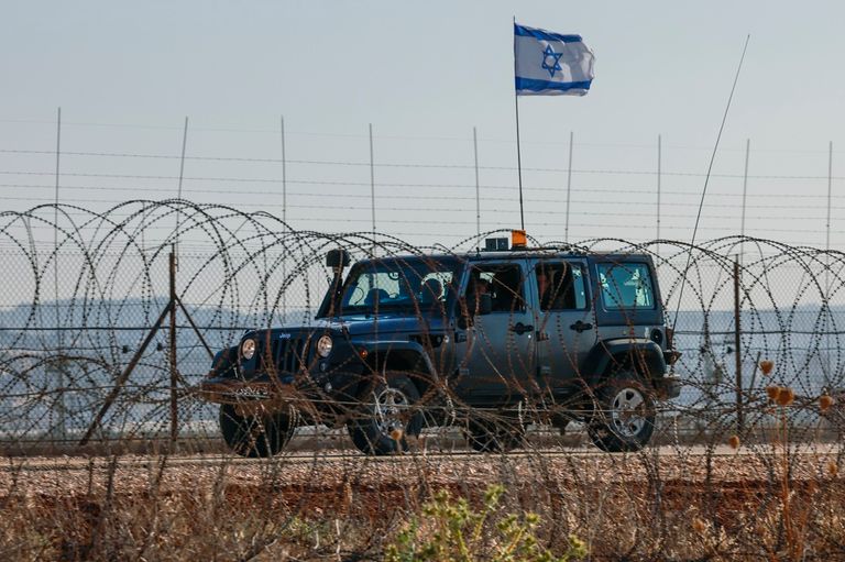 فلسطيني يحمل علما وسط النيران جراء المواجهات في جنين