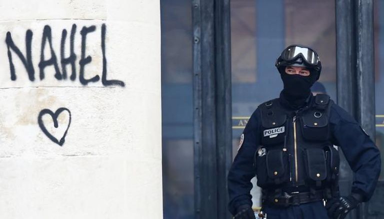 شرطي فرنسي قرب جدار كتب عليه المحتجون اسم نائل