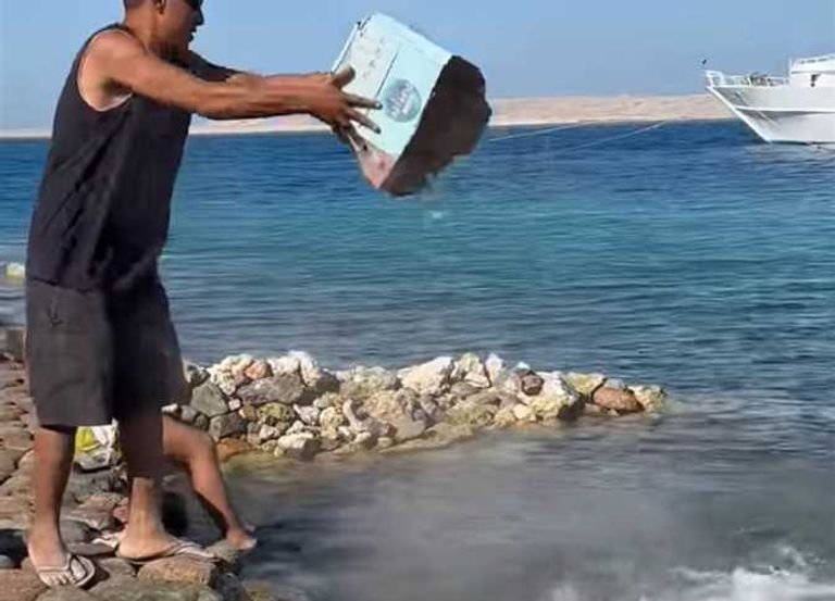 مصري يلقي زجاجا مكسورا في شواطئ الغردقة