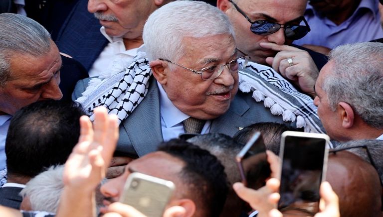 الرئيس الفلسطيني متشحا بالكوفية وممسكا بغصن الزيتون خلال زيارة جنين