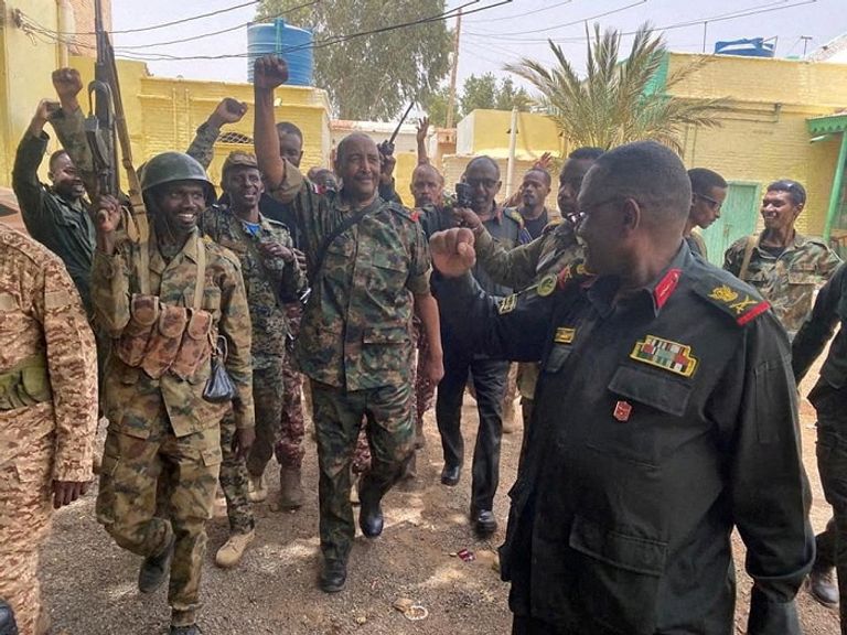 البرهان وسط بعض جنود الجيش السوداني الدخان يتصاعد من مواقع الاشتباكات في الخرطوم