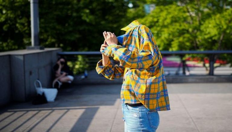 شخص يستخدم الملابس لحماية نفسه من أشعة الشمس أثناء سيره في شنغهاي- رويترز
