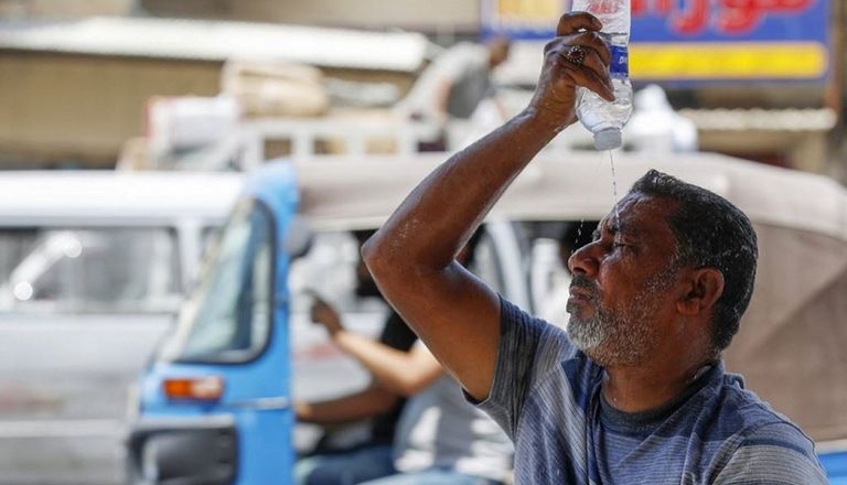 رجل يبرد جسده في الحر الشديد بالوقوف أمام المراوح