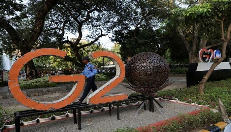 حارس أمن يسير أمام نموذج لشعار مجموعة العشرين خارج حديقة في نيودلهي