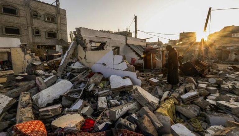 سكان يبحثون بين أنقاض منزل دمره القصف الإسرائيلي في مخيم رفح للاجئين جنوب غزة