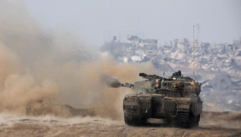 دخان يتصاعد من دبابة إسرائيلية وفي الخلفية بيوت مدمرة بقطاع غزة
