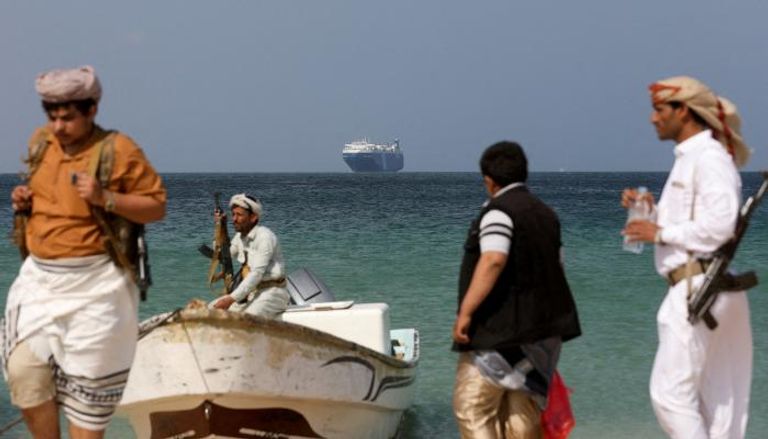 مسلحون حوثيون على ساحل البحر الأحمر وفي الخلفية سفينة محتجزة - رويترز