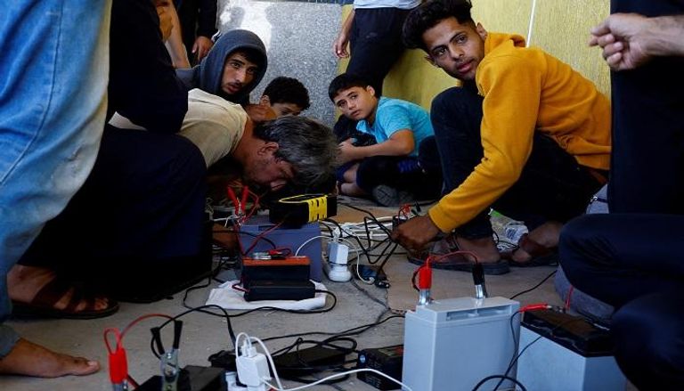 فلسطينيون يشحنون هواتفهم المحمولة من نقطة تعمل بالألواح الشمسية - رويترز