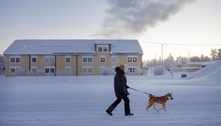 مواطن سويدي يصطحب كلبه في جولة على الثلج - رويترز