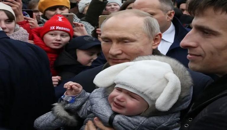 بوتين يحمل طفلا خلال زيارة لإحدى مناطق روسيا