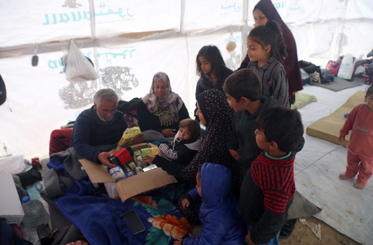 متطوعة تقدم طردًا غذائيًا لأسرة فلسطينية