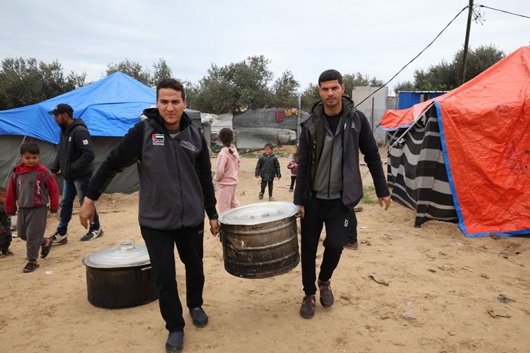 متطوعة تقدم طردًا غذائيًا لأسرة فلسطينية