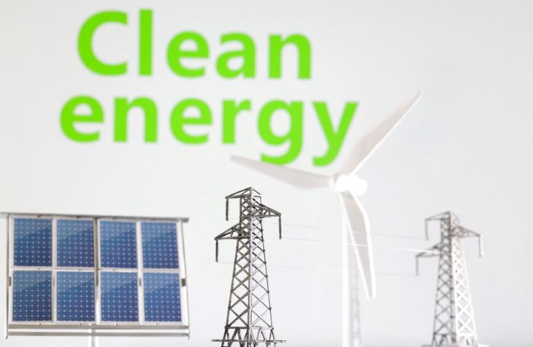 طاحونة هواء وألواح شمسية وعمود كهربائي أمام عبارة "الطاقة النظيفة" - رويترز جو بايدن ودونالد ترامب - رويترز