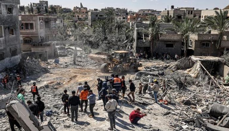فلسطينيون يفحصون أنقاض مبنى انهار في أعقاب غارة إسرائيلية بغزة
