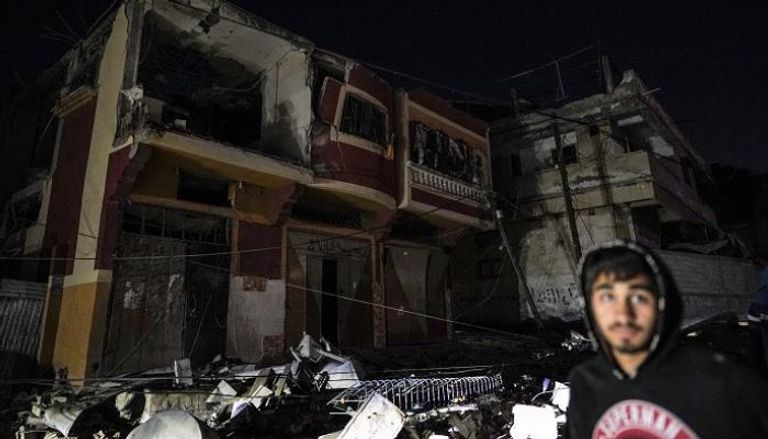 شاب فلسطيني أمام منزل استهدفته إسرائيل بغزة