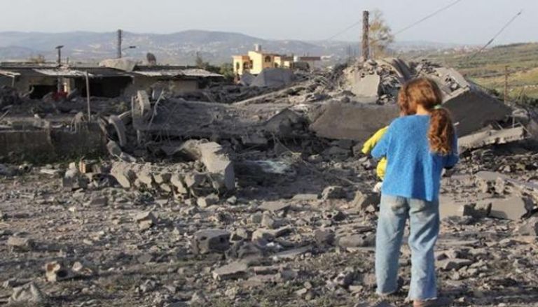 فتاة تتفقد الأضرار التي لحقت بمبنى بعد غارة إسرائيلية سابقة على قرية بلبنان