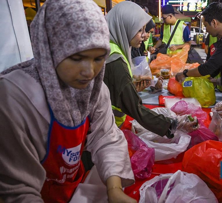 متطوعو المنظمات غير الحكومية من بيمودا جيما يتفقدون جودة الأطعمة التي يقدمها لهم بائعو بازار رمضان وإعادة تعبئتها في بازار كي جي بارو الرمضاني في كوالالمبور في 3 أبريل 2024 متطوعون يجمعون طعاما تبرع به أحد البازارات لصالح الفقراء في كوالالمبور
