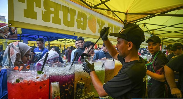 بائعون يبيعون أنواعًا مختلفة من المشروبات في البازار الرمضاني في كغ بارو، كوالالمبور في 3 أبريل 2024. متطوعون يجمعون طعاما تبرع به أحد البازارات لصالح الفقراء في كوالالمبور