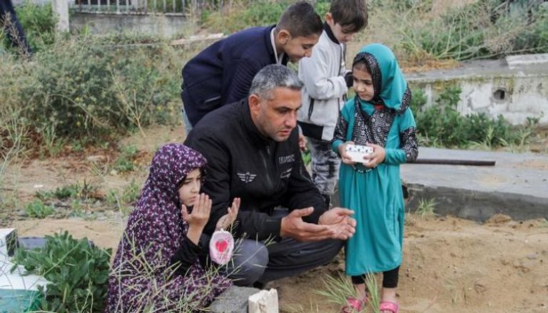 أسرة فلسطينية تزور المقابر بغزة - أ.ف.ب