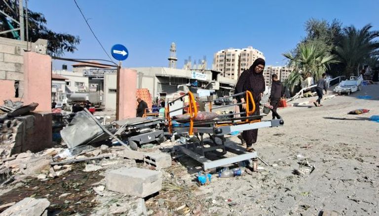 فلسطينية تتفحص بقايا معدات بأطراف مخيم جباليا