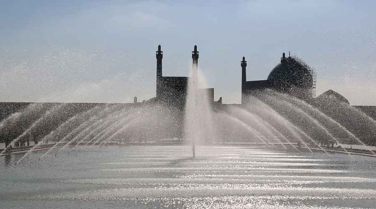 زوار يلتقطون الصور بجوار النافورة في ساحة نقش جهان التاريخية